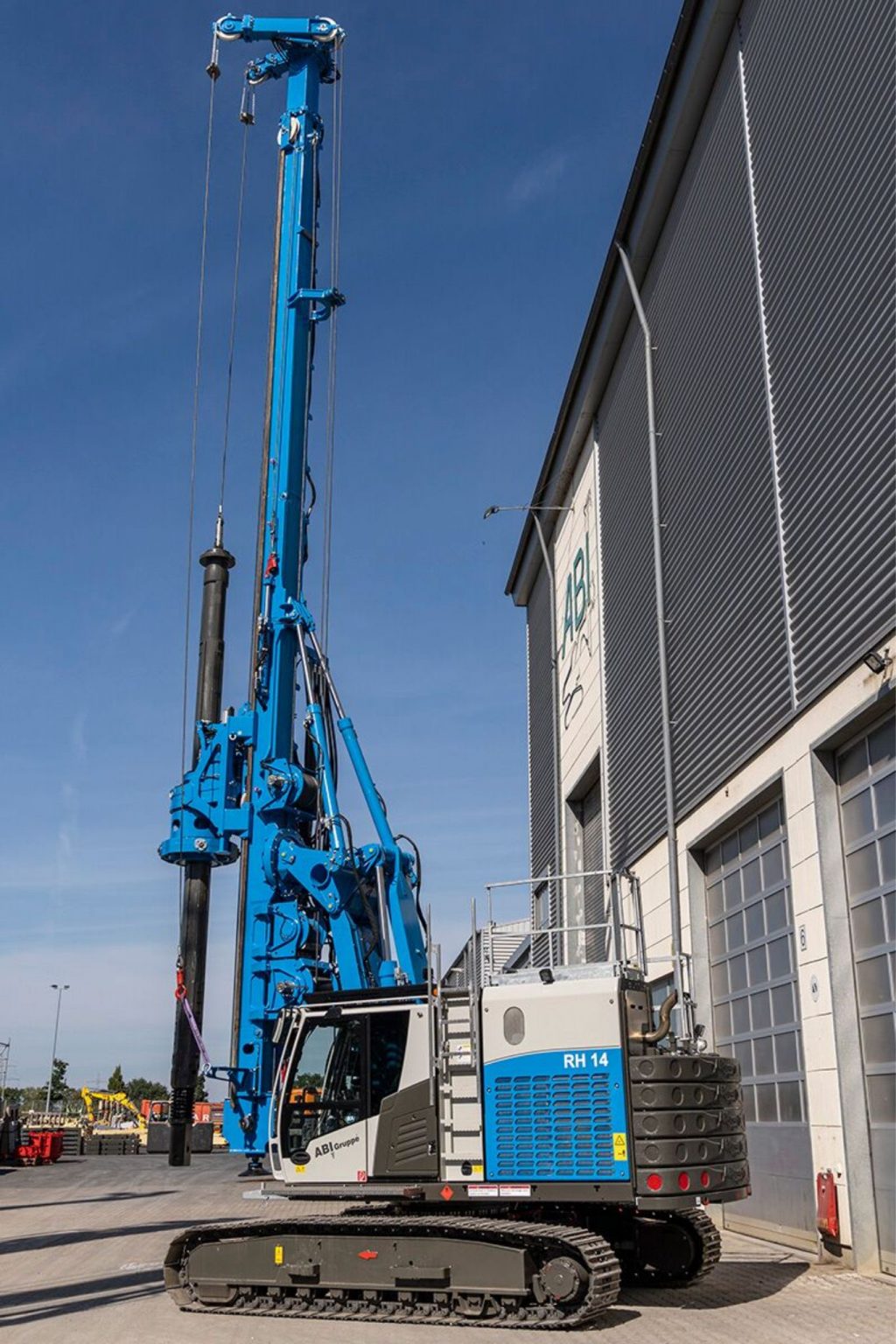 Delmag RH 14 rotary drill rig in blue finish near an industrial building
